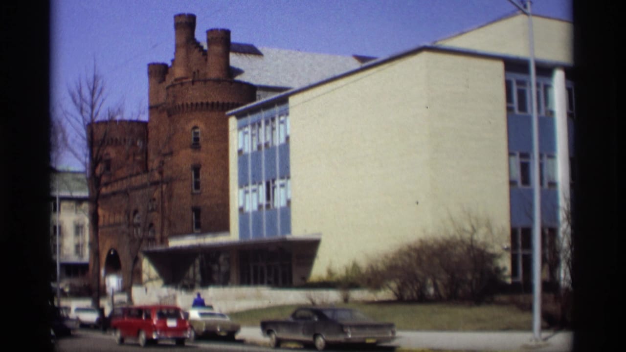 Madison, Wisconsin exterior view of a blue-and-white institutional building and brick tower, with cars parked along the street.