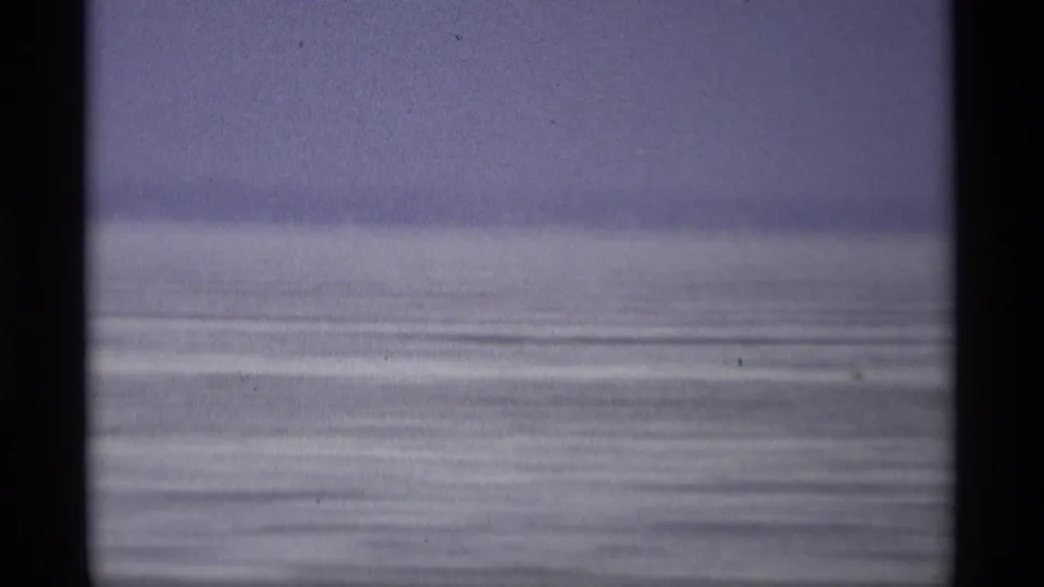 1966 Madison, Wisconsin home-movie view of broad lake water under a pale sky, with dark vertical edges from the filming position.