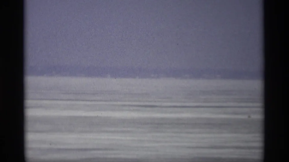 1966 Madison home-movie frame showing a pale frozen field or water surface beneath an overcast sky.