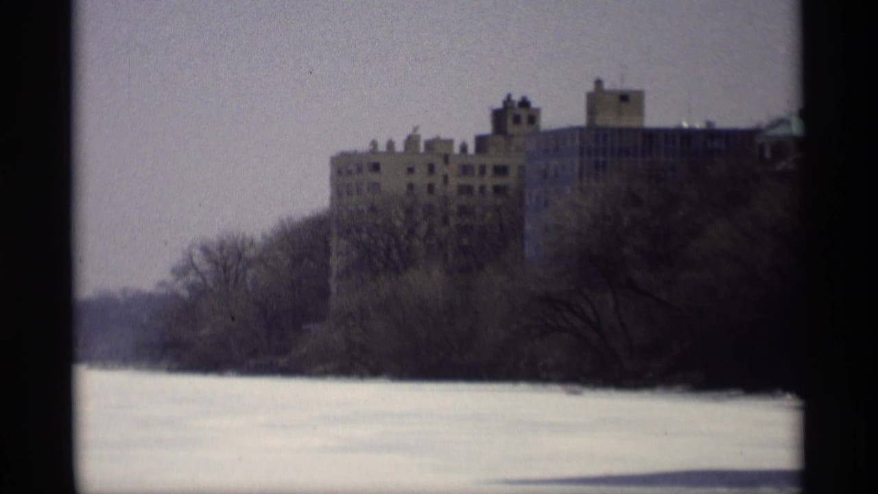 1966 Madison view of a large brown building rising behind leafless trees at the edge of a frozen winter expanse.