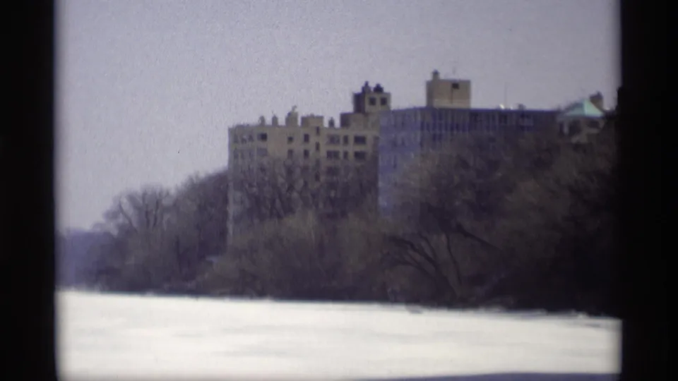 1966 Madison 8mm frame showing a brown multi-story building behind bare trees across a frozen winter foreground.