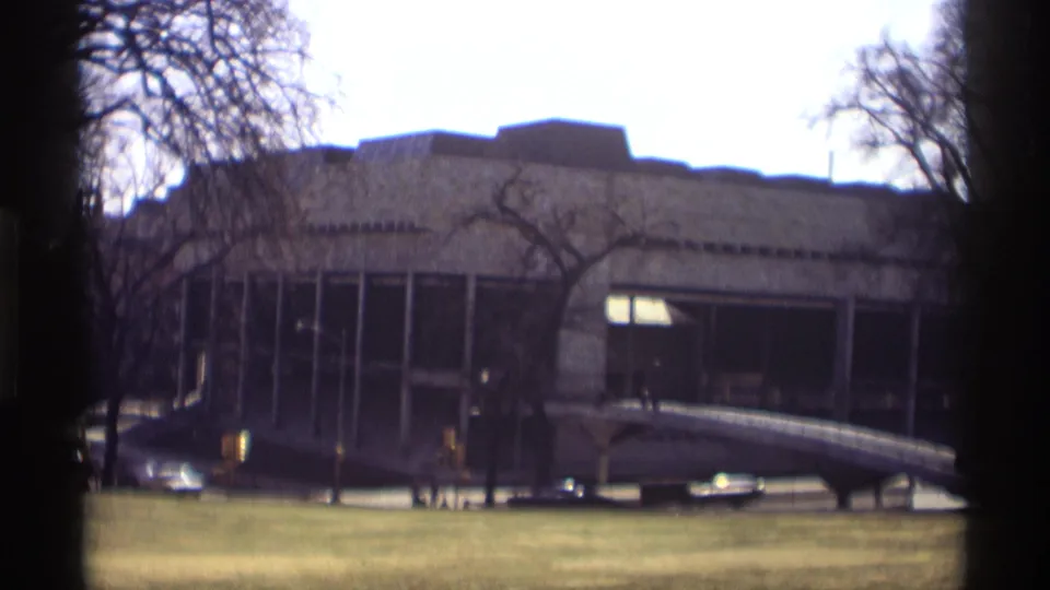 1966 Madison exterior view of a modernist building with tall windows, bare trees, a lawn, and a curved ramp-like structure.