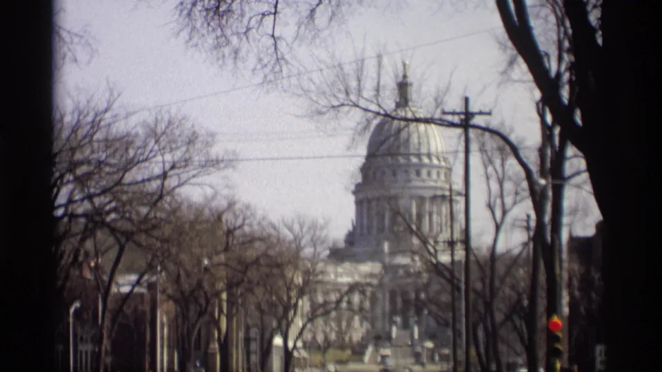 Madison street view of the Wisconsin State Capitol dome and facade, softened by 8mm grain and motion blur.