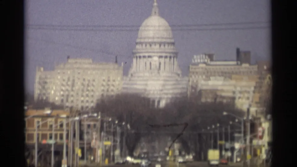 Madison, Wisconsin skyline view with the State Capitol dome, downtown buildings, bare trees, wires, and a soft, grainy 8mm film texture.
