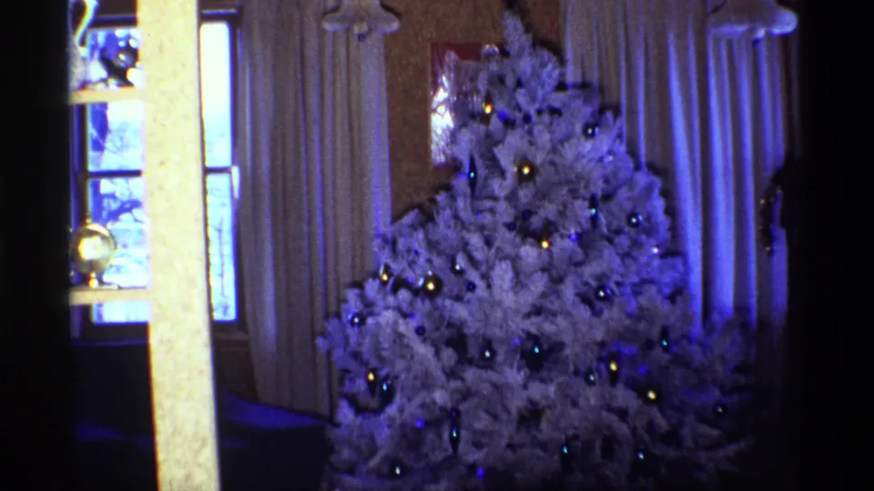 1968 Chicago home-movie frame with the decorated white Christmas tree filling most of the interior view.
