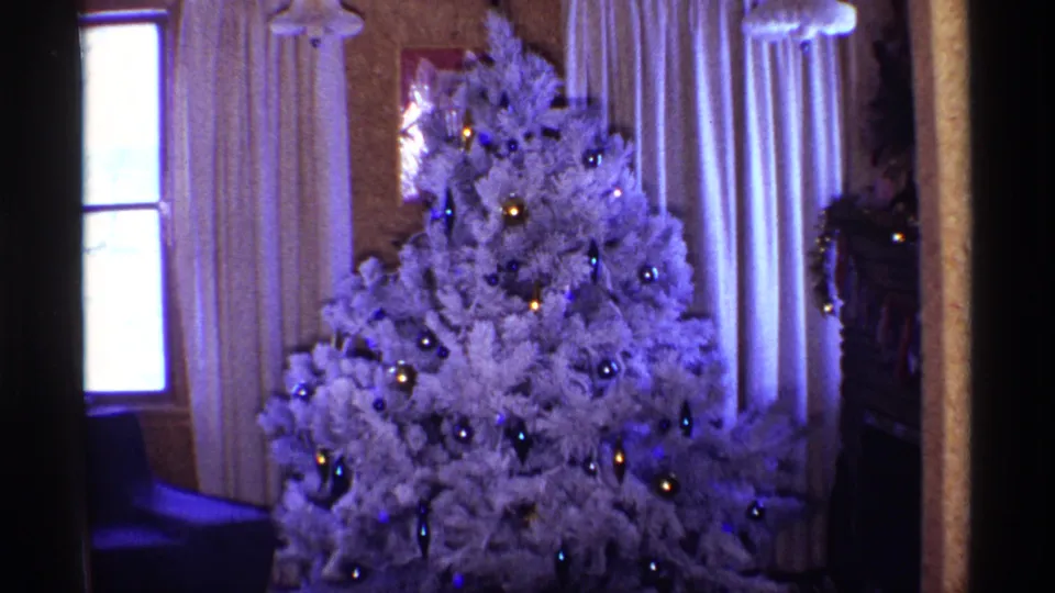 Final 1968 Chicago 8mm frame of the white Christmas tree with ornaments, lights, curtains, and a bright window nearby.