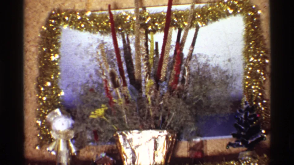 1968 Chicago home-movie frame showing a glittering holiday centerpiece, dried stems, and small tabletop decorations in a private interior.