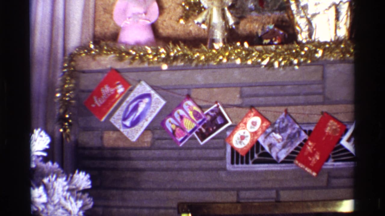 Christmas cards strung across a brown stone fireplace with tinsel on the mantel.