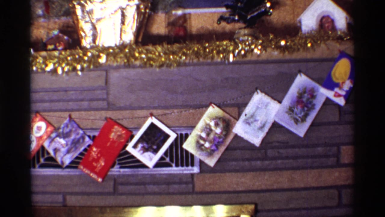 1968 Chicago home interior detail showing several Christmas cards strung in front of a brown stone fireplace, with tinsel and small decorations above.