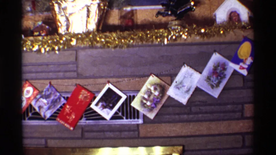 1968 Chicago home interior detail showing several Christmas cards strung in front of a brown stone fireplace, with tinsel and small decorations above.