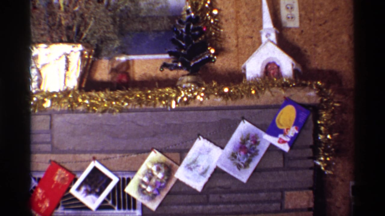 Chicago 1968 Christmas mantel detail showing a row of holiday cards below gold tinsel, with a foil planter, small tree, and white church model.