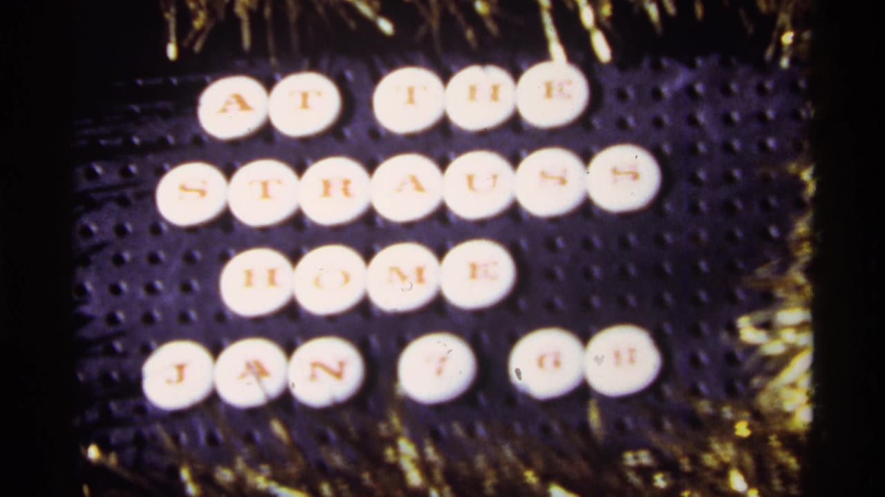 Letter tiles on a dark background spell out a dated Strauss home message, framed by gold tinsel in the 1968 home-movie clip.