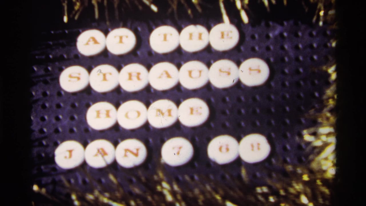 Close 1968 home-movie view of the circular tiles reading “AT THE STRAUSS HOME JAN 7 68” beside gold holiday tinsel.