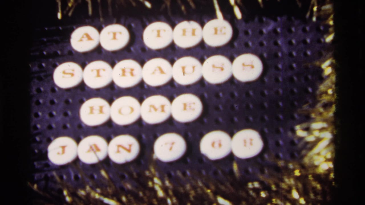 A 1968 Chicago home-movie frame centers the dated Strauss home letter-tile sign, with gold tinsel visible around the board.