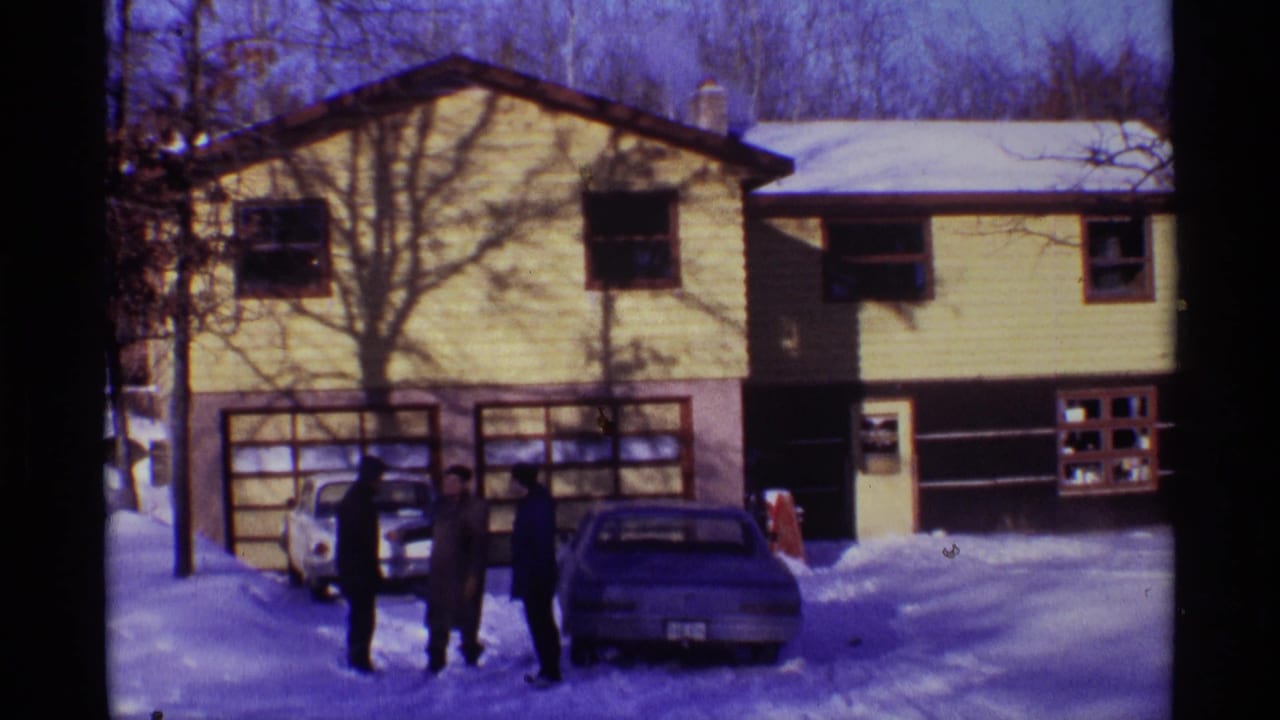 In Chicago home-movie footage from 1968, three men stand in winter coats outside a yellow-sided house beside two parked cars.