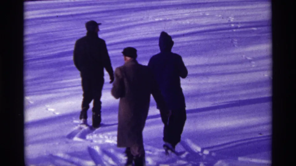 Bundled men in coats and hats move across a snowy Chicago scene, seen in purple-tinted 8mm footage.