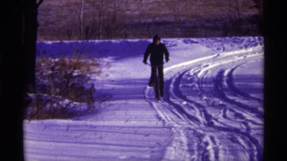 A cyclist rides toward the camera on a snowy path in 1968 Chicago, with tracks curving through the snow.