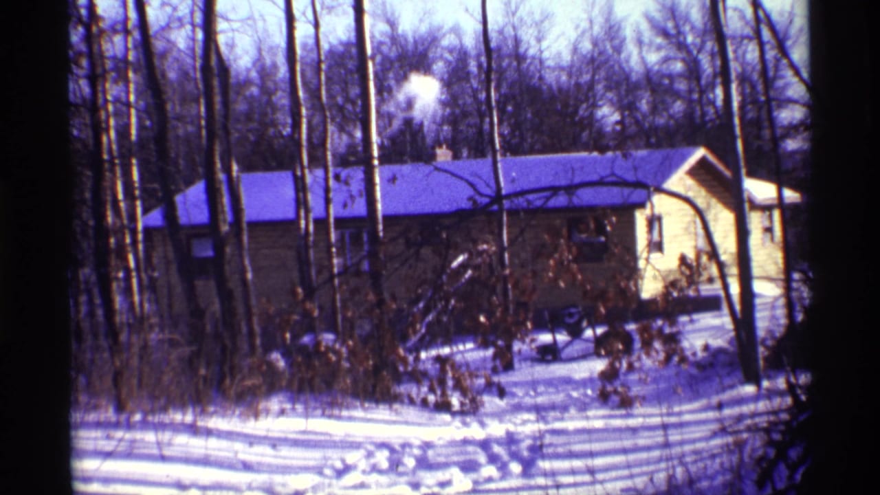 1968 Chicago 8mm frame showing a yellow house with a smoking chimney among bare trees and snow.