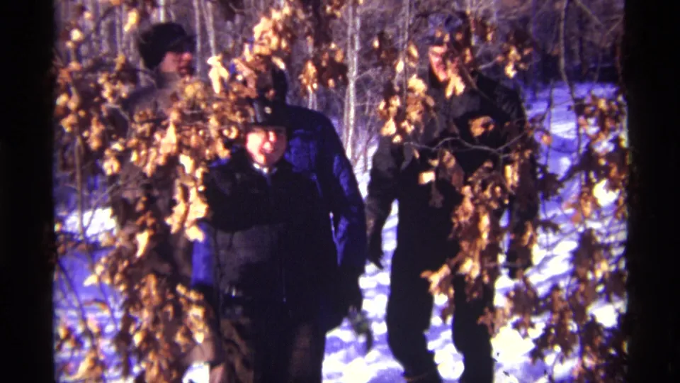 Bundled figures, including visible faces, walk through a snowy wooded area in this 1968 Chicago home movie frame.