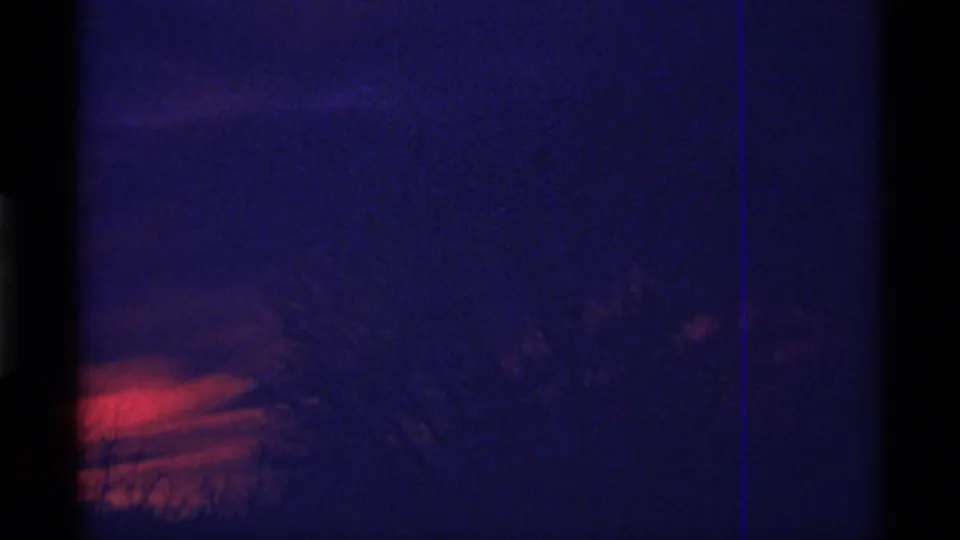 1968 Chicago 8mm frame with a blue dusk sky, red-orange sunset glow, and soft dark tree shapes near the horizon.
