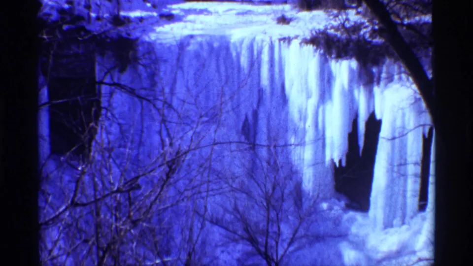 Chicago metadata places this 1968 8mm frame at a winter waterfall, with hanging ice, snow, bare branches, and saturated blue film color.