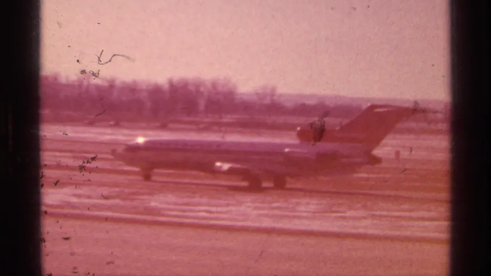 Color-shifted 1968 Chicago airport frame with a Northwest Airlines jet partly softened by exposure and film wear.