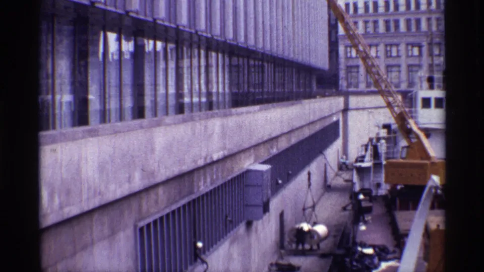 A 1968 Chicago construction scene with a crane, concrete facade, glass windows, and older buildings in the background.