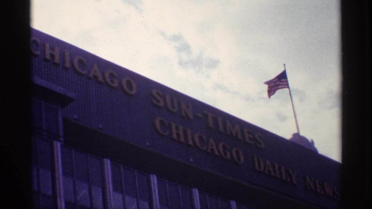 Angled view of Chicago newspaper building signage and a rooftop American flag.