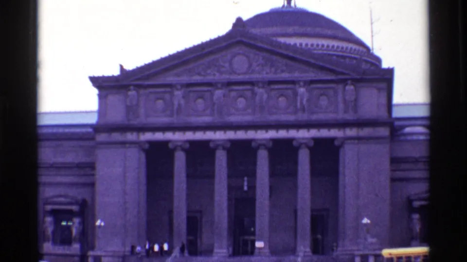 1968 Chicago 8mm frame of a grand classical building with columns, a decorated pediment, dome, and pedestrians near the doorway.