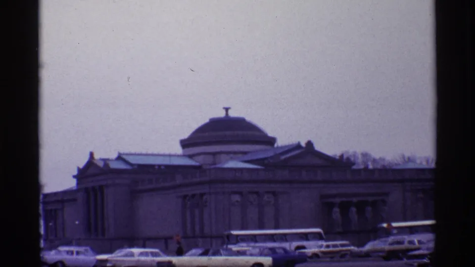 1968 Chicago frame showing the domed building from a slightly lower angle with cars and a bus near the curb.