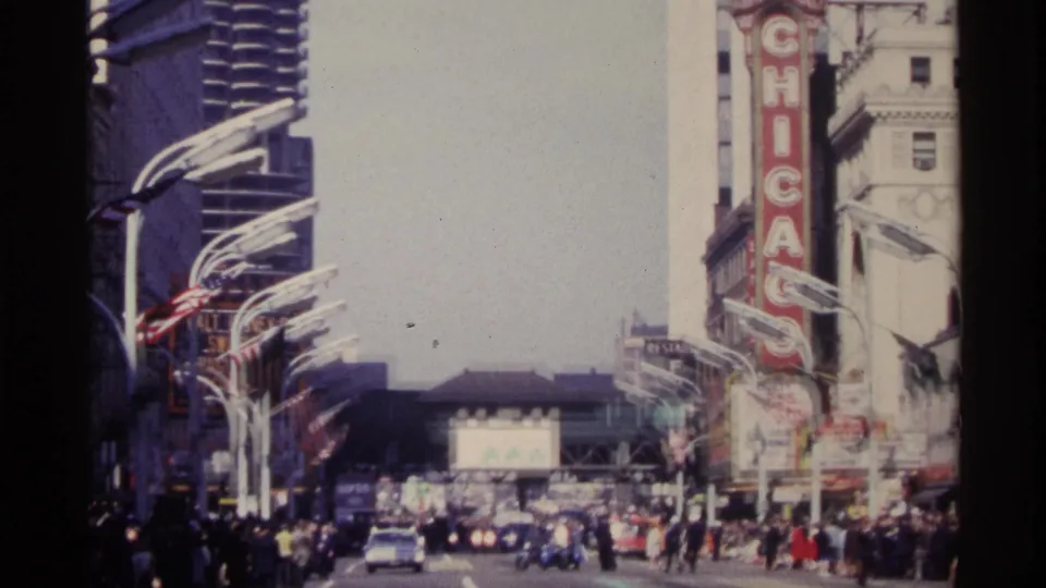 1968 Chicago home-movie frame showing the Chicago Theatre marquee above a crowded downtown street with moving cars.