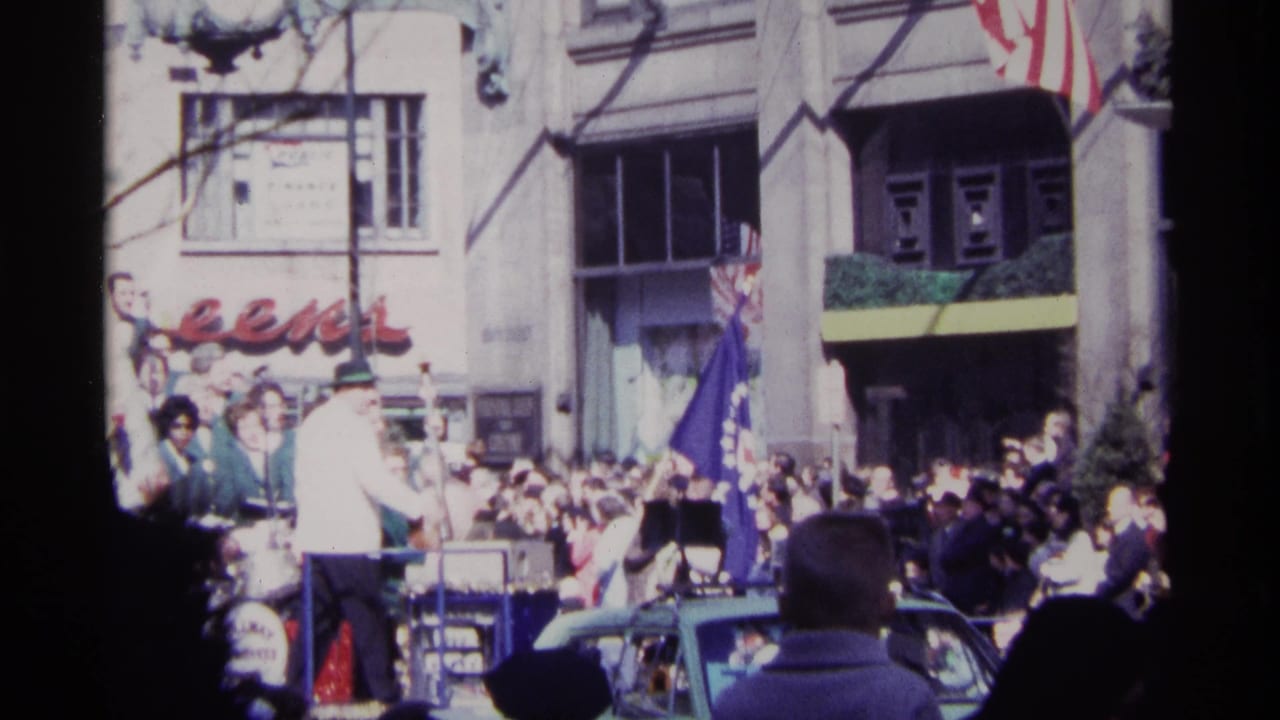 Parade float with conductor facing a band and crowd-lined Chicago street.