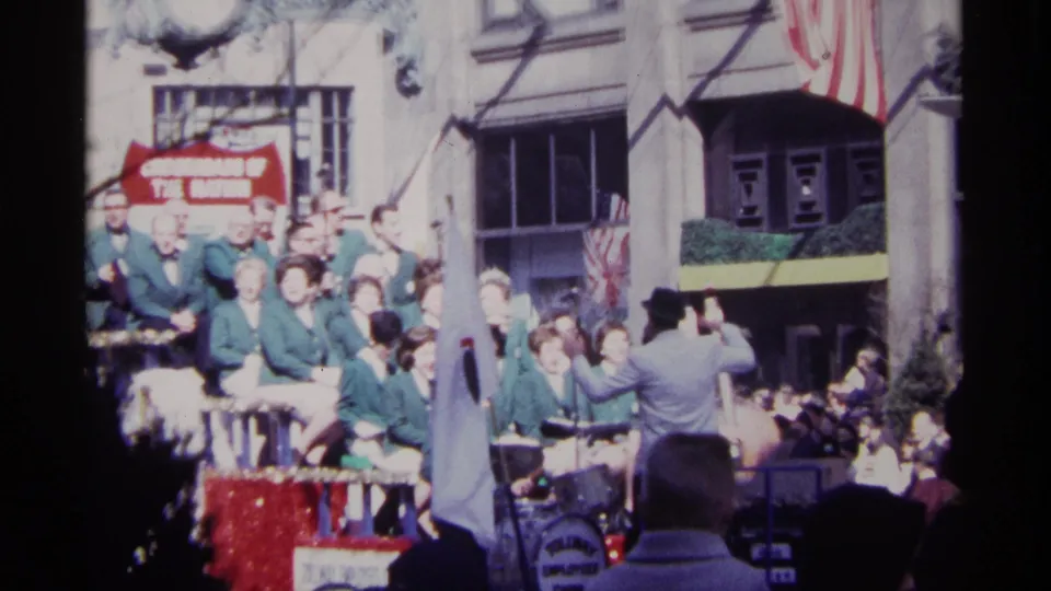 Chicago parade footage from 1968 shows band members on a decorated float, a conductor gesturing, banners, flags, and spectators.