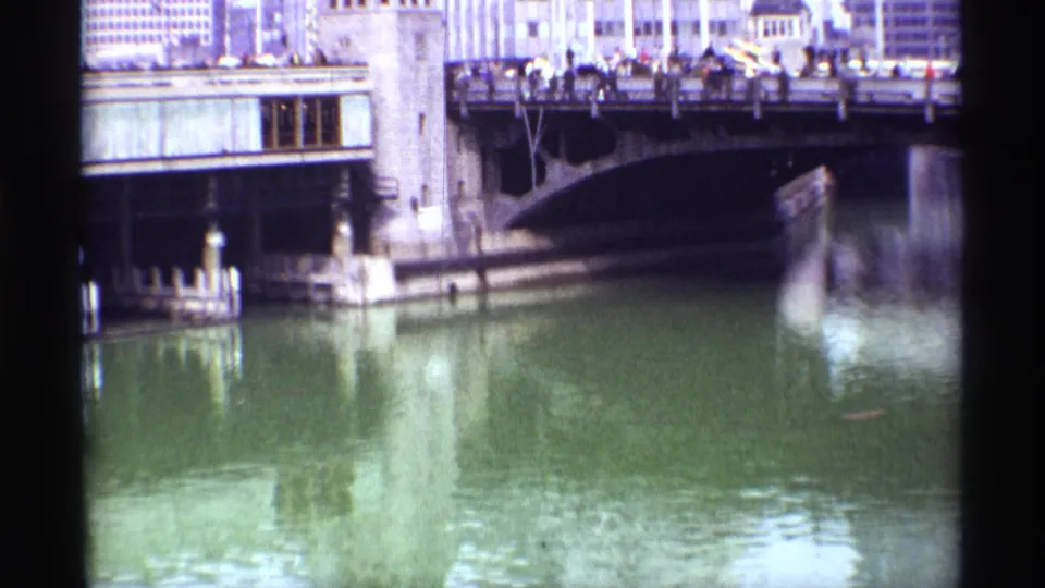 Chicago bridge scene from 1968 showing a busy span, distant pedestrians and vehicles, stone bridge elements, and soft river reflections.