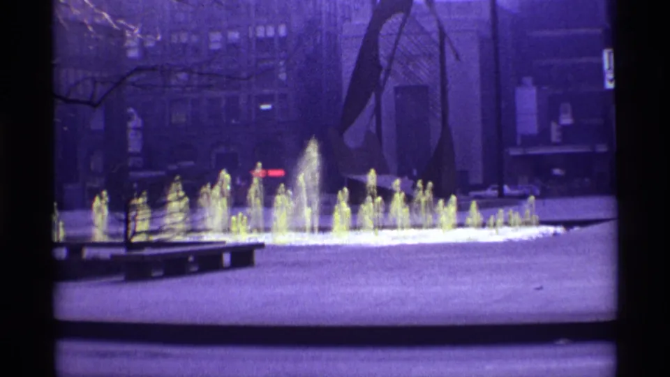 A purple-tinted 8mm view of the Chicago plaza fountain, with the walking man mostly leaving the shot.