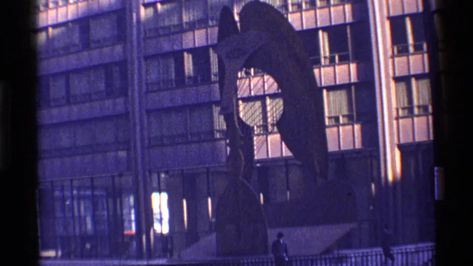 1968 Chicago home-movie frame of an abstract outdoor sculpture seen against a modern glass-and-window building.