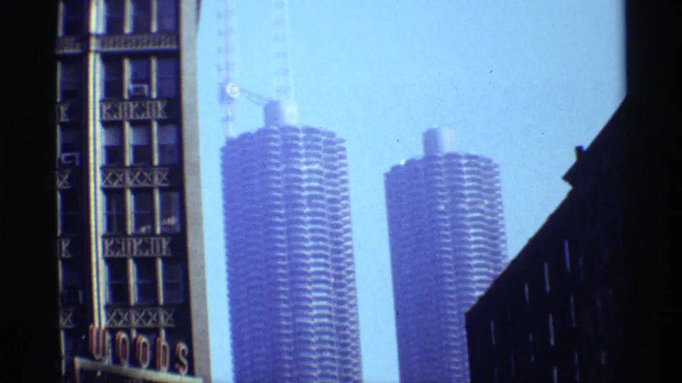 1968 Chicago frame showing two cylindrical high-rise towers, likely Marina City, with cranes and darker foreground building edges.
