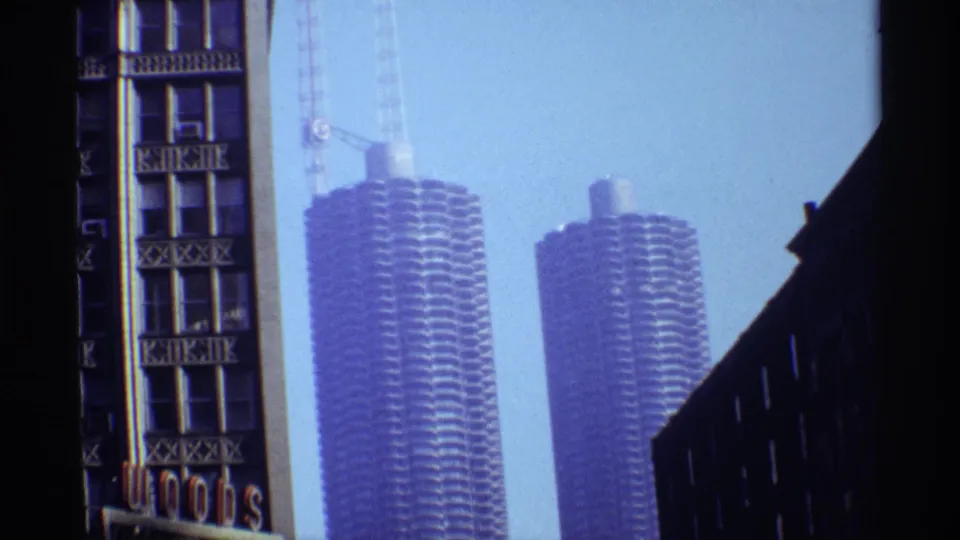 Chicago 1968 skyline view with two cylindrical towers, likely Marina City, seen between darker foreground structures and a clear sky.