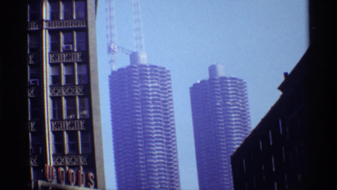 Marina City towers under construction seen beside an older building facade with vertical signage.