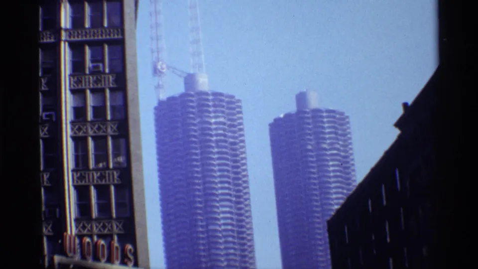 1968 Chicago view of Marina City towers under construction, with cranes visible beyond an older downtown building facade.