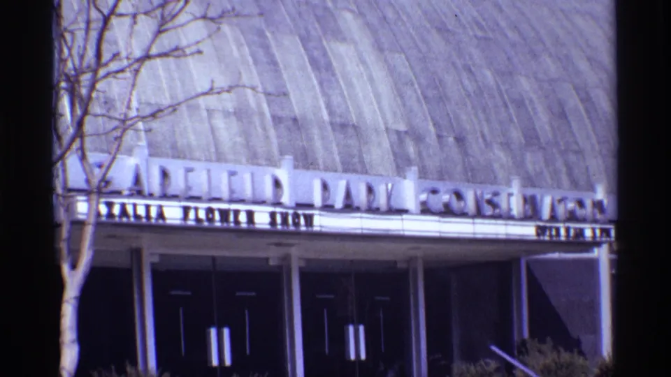 Exterior view of Garfield Park Conservatory in Chicago, showing the domed roof, entrance doors, marquee lettering, and bare tree branches.