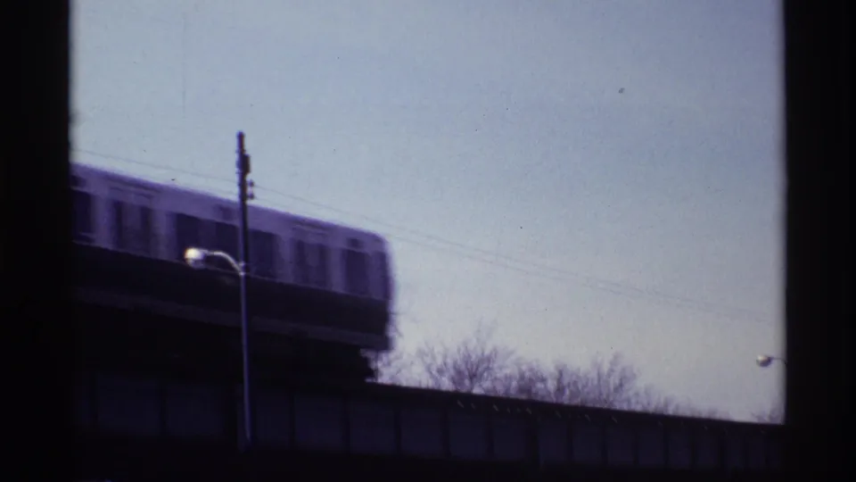 Chicago elevated train cars move across an elevated track, blurred by motion in the 8mm frame.