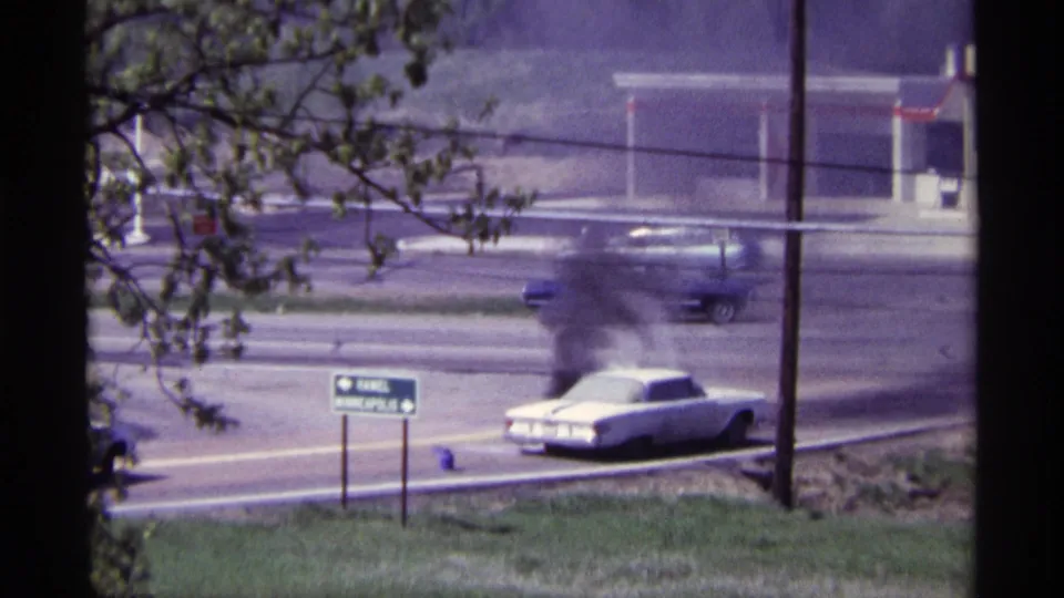 At the end of the clip, heavy smoke obscures part of the white car on the Chicago-area road near signage and a service station.