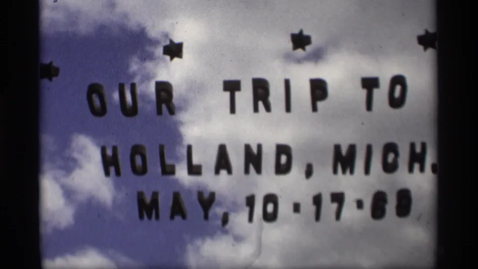 Close 8mm frame of the Holland, Michigan trip title card, with the date May 10-17-69 set against a cloudy sky.