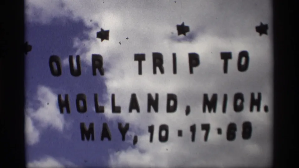 Soft 8mm frame of the homemade Holland, Michigan vacation title card with date text and star decorations visible.