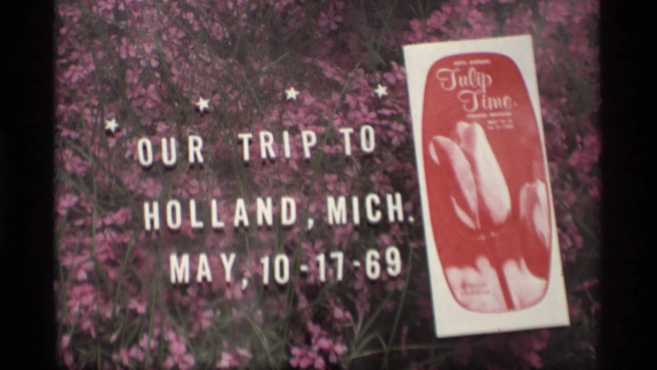 Title card on pink flowers with a Tulip Time program booklet beside white lettering.
