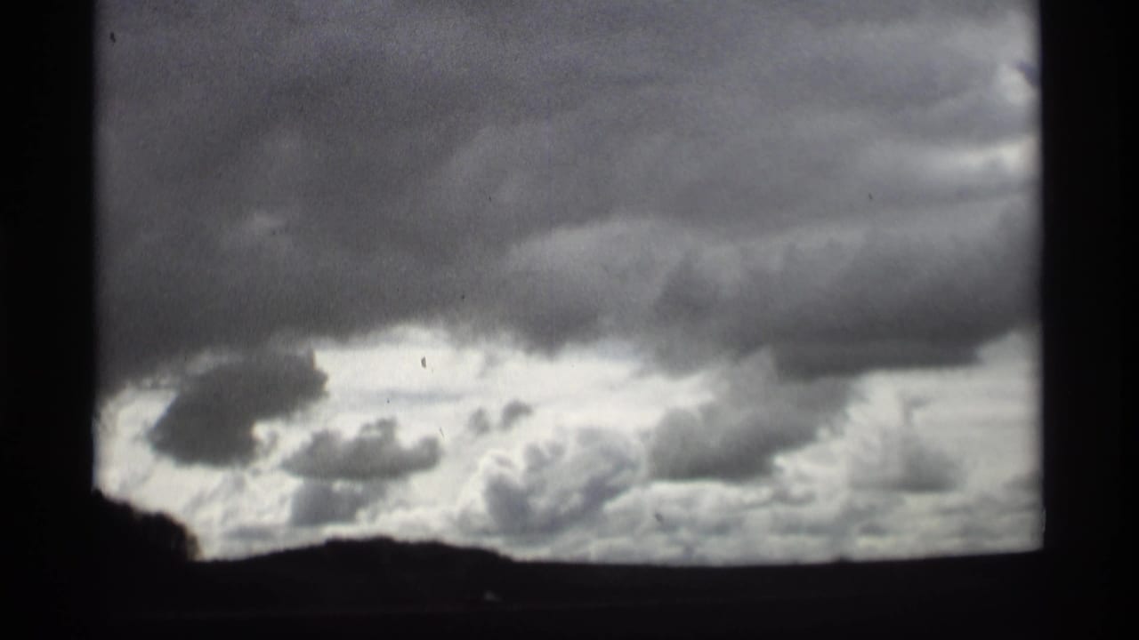 1969 Holland, Michigan 8mm frame showing heavy gray clouds over a dark low horizon.