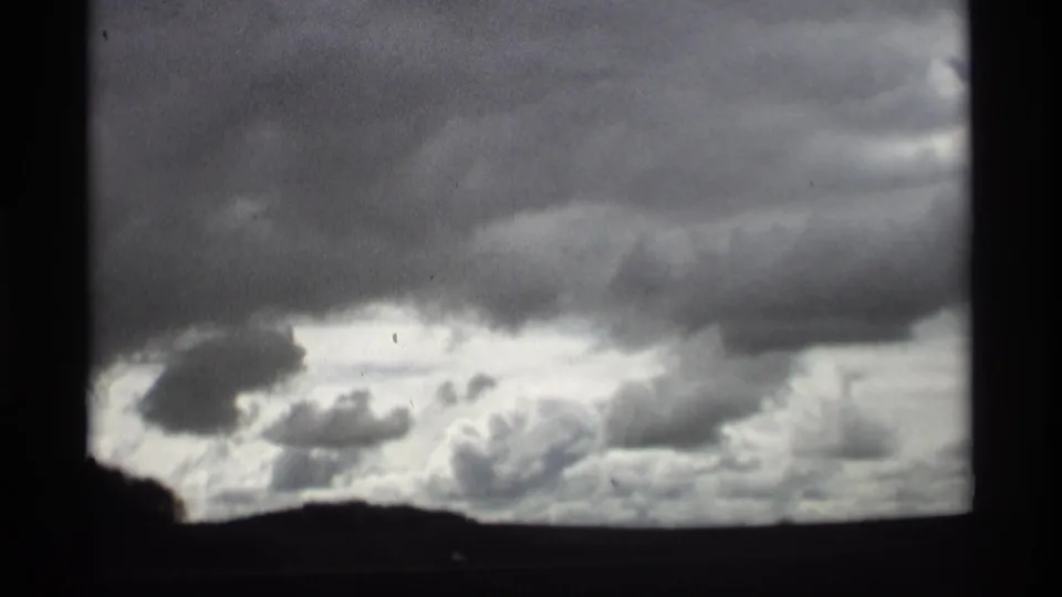1969 Holland, Michigan 8mm frame showing heavy gray clouds over a dark low horizon.