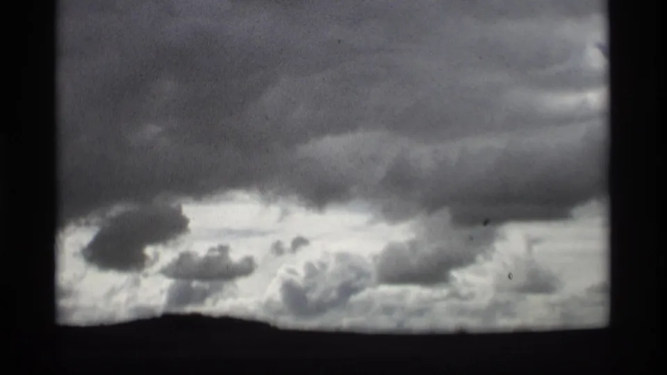 1969 Holland, Michigan home-movie frame with layered storm clouds and a low dark horizon.