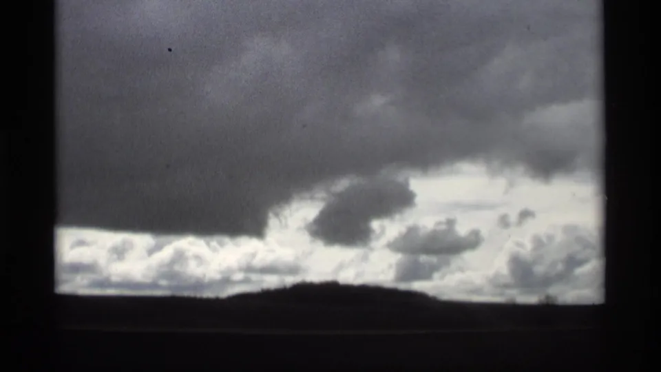 1969 Holland, Michigan 8mm frame showing a dark cloud mass above brighter clouds near the horizon.